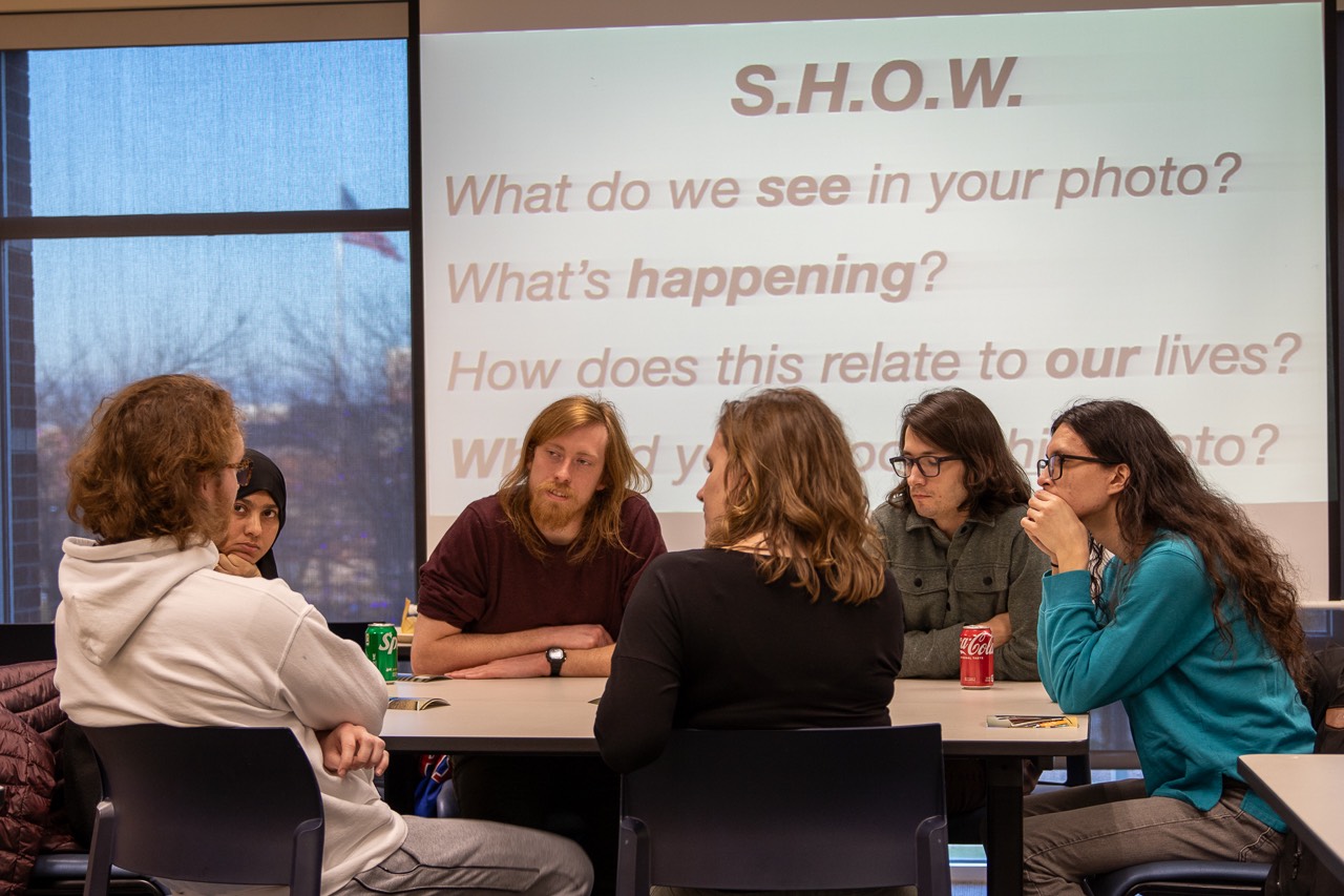 Group of people talking with powerpoint slide in the background